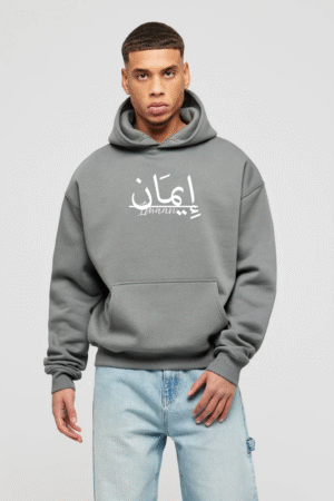 "Model wearing a grey oversized hoodie featuring Arabic calligraphy 'Imaan', representing VedFra Clothing & Co.’s Islamic-inspired streetwear collection."