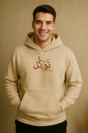 Smiling man wearing beige hoodie with Arabic “Tawakkul” design – faith-inspired streetwear by VedFra