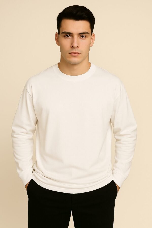 Oversized white full sleeve tee worn by a young man smiling subtly, shot in natural light.